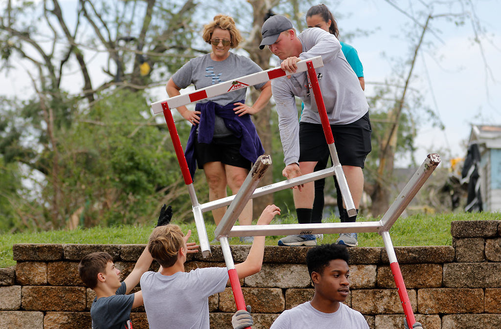 Coaches and athletes from the Jefferson City High School athletics teams work to clean campus